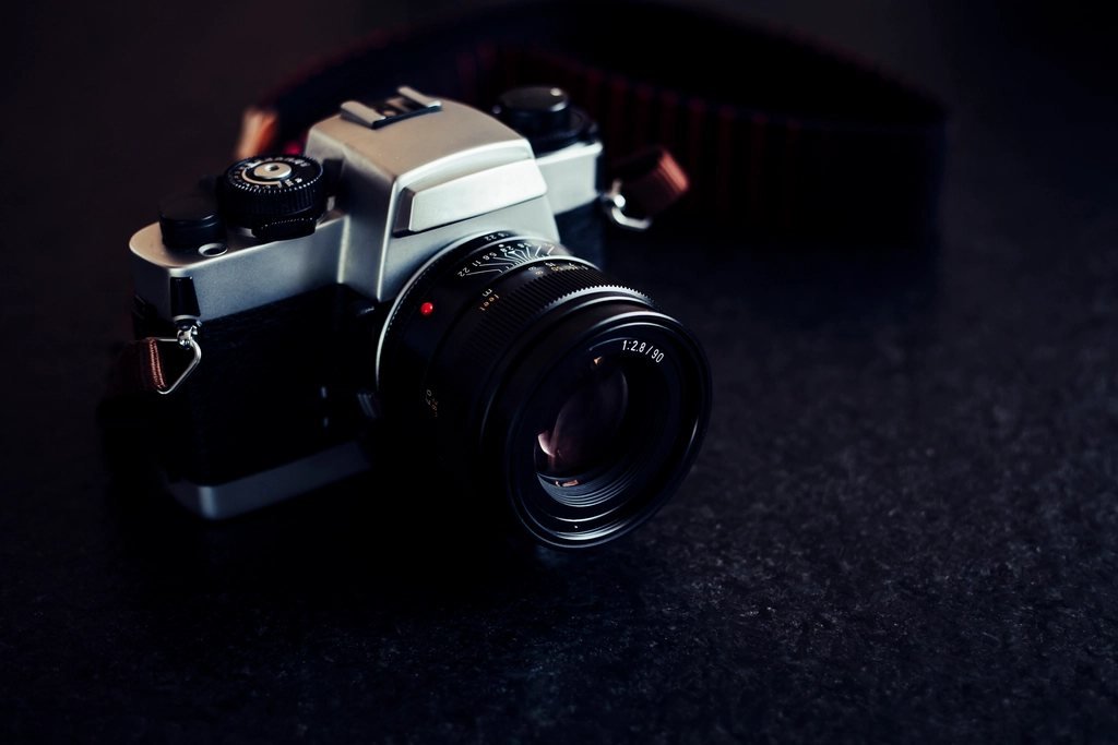 A camera with a large lens sitting on a dark table