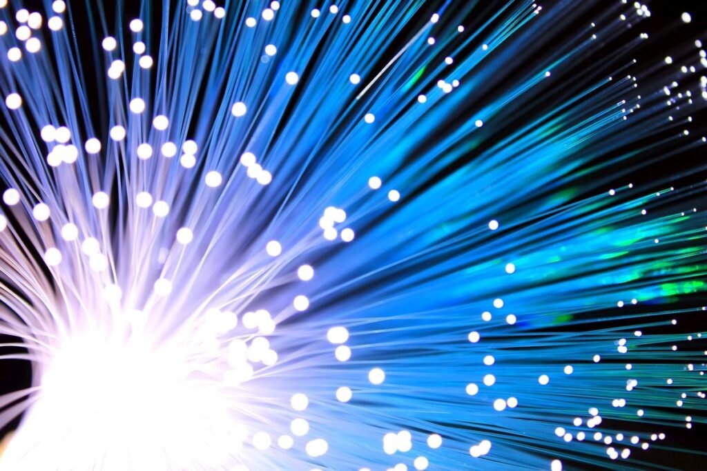 Strands of fiber optic cable glowing blue and white at their tips
