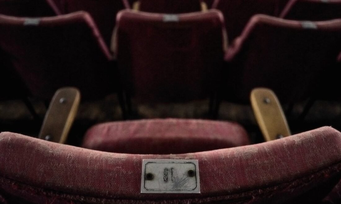 Rows of red velvet seats in an empty movie theater
