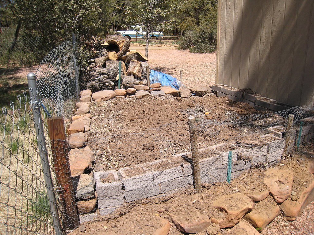 A raised garden bed built from stacked blocks and stone, ready for planting